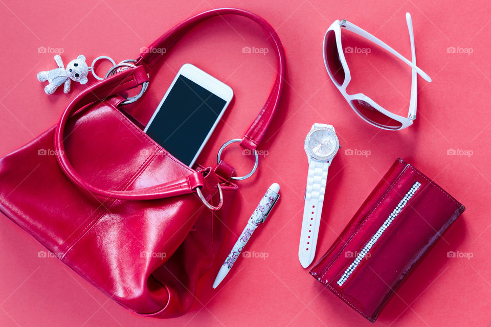 Smartphone sunglasses wallet and other things pulled out of handbag put on a table