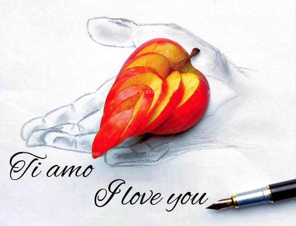 A black and white male hand is drawn on a white sheet, on which lies a red cut apple in the form of a heart. At the bottom of the painting is written: "I love you" in Italian and English. Next to it is a ink pen