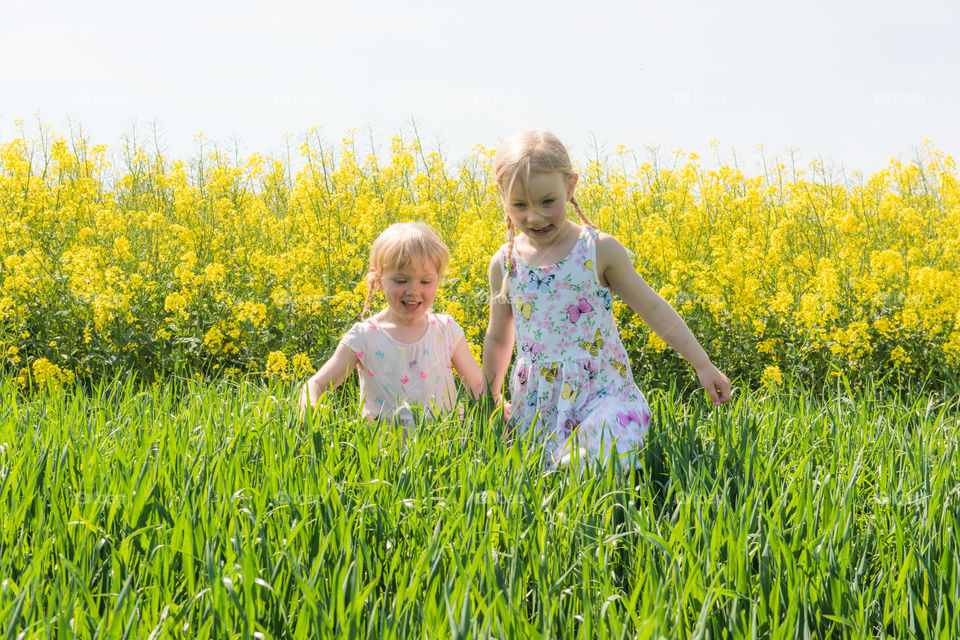 Two young sisters a running in a Raps field outside Malmö Sweden.