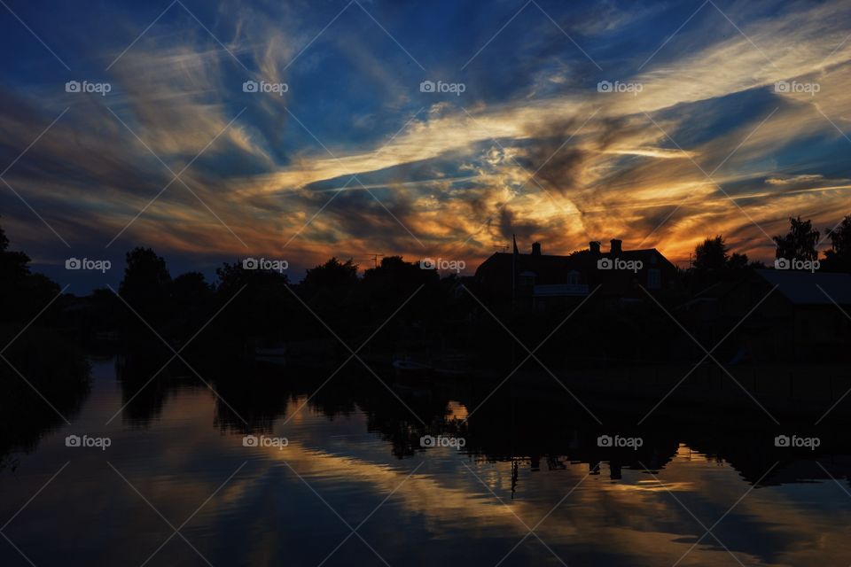 Silhouette of trees by lake at sunset