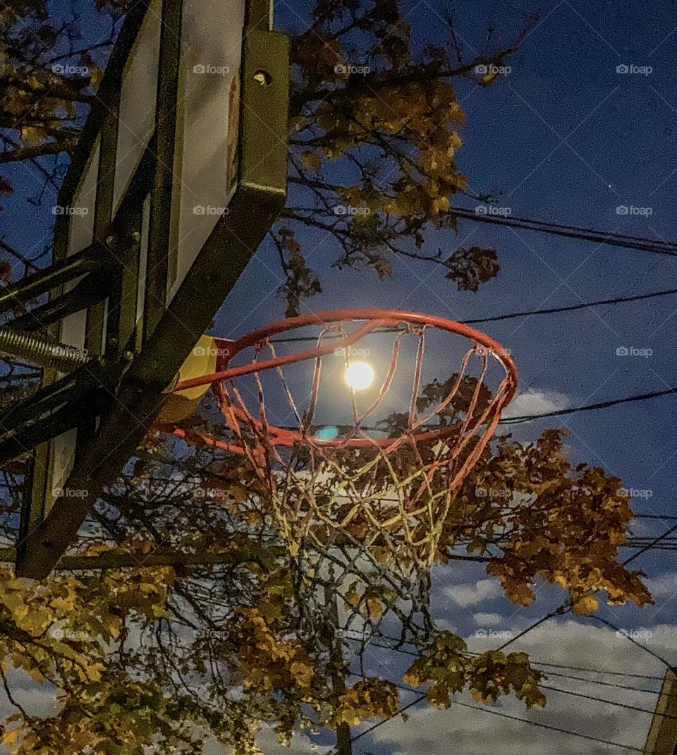 The full moon captured through the hop of a basketball hoop. Nothing but net.