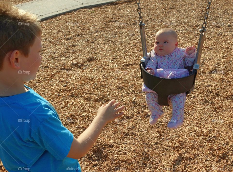 Big Brother Pushing Baby In A Swing