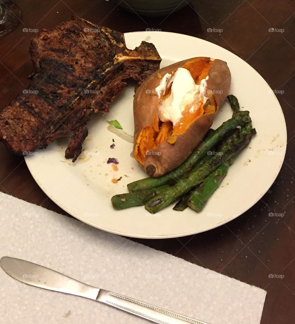 Steak, sweet potatoes and asparagus on a plate.