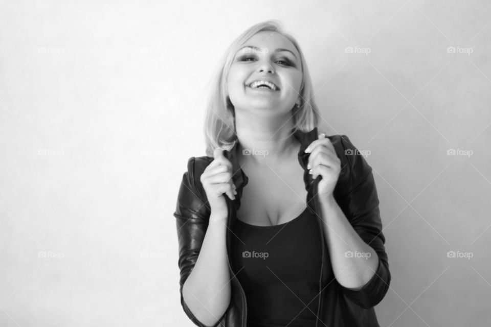 A blonde girl on a white background in a black leather jacket expresses her emotions and feelings (joy, sadness, amorousness, femininity, sensuality, tenderness)