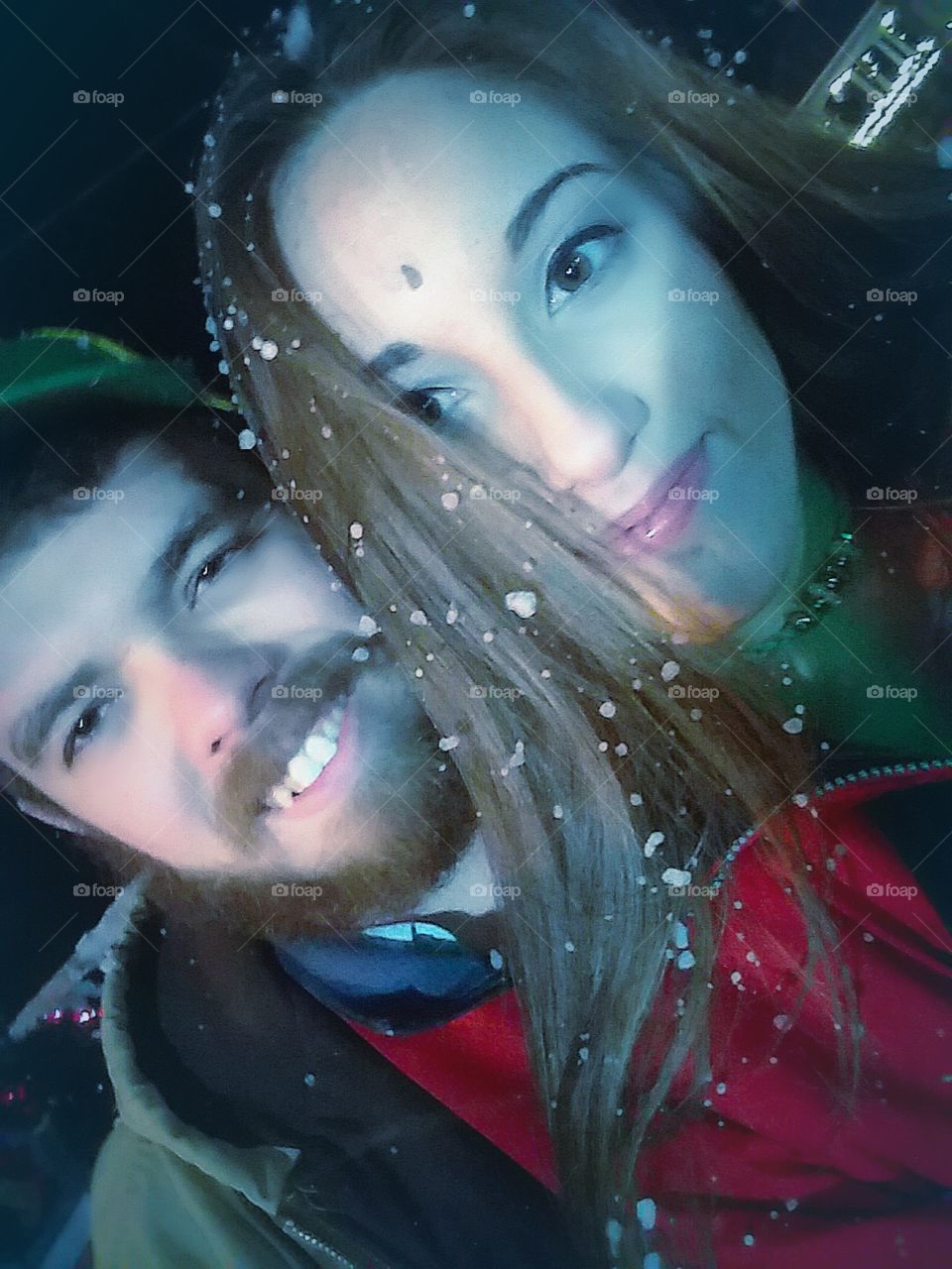 A beautiful young couple playing together in the snow in the winter months smiling portrait