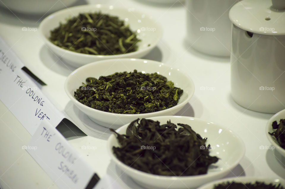 Green tea leaves in bowls ingredients for healthy diet and lifestyle on table with white table cloth and porcelaine bowls 