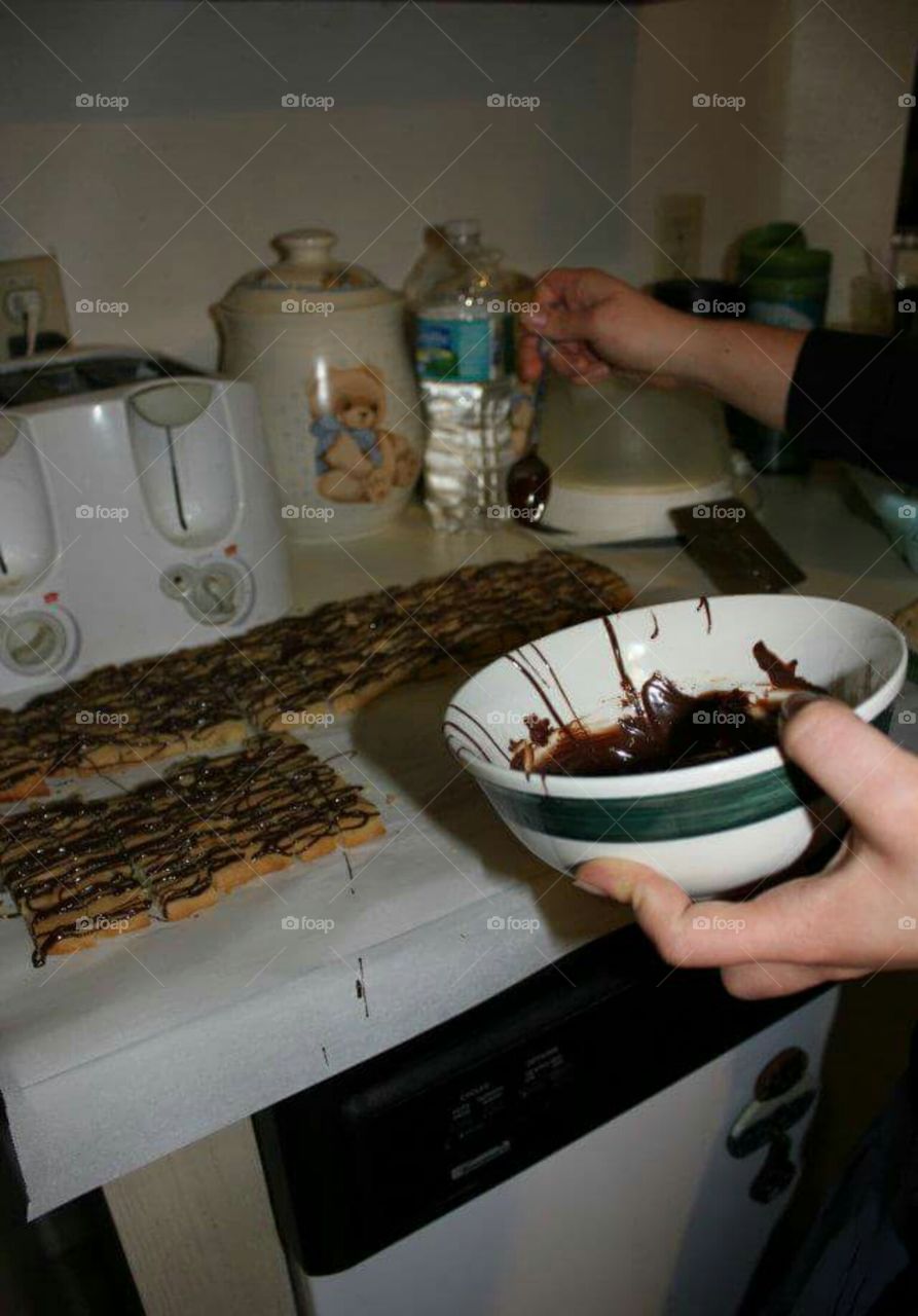 Adding chocolate to the top of the biscotti.