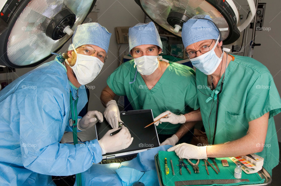 Three men operate on the computer on the emergency room table in