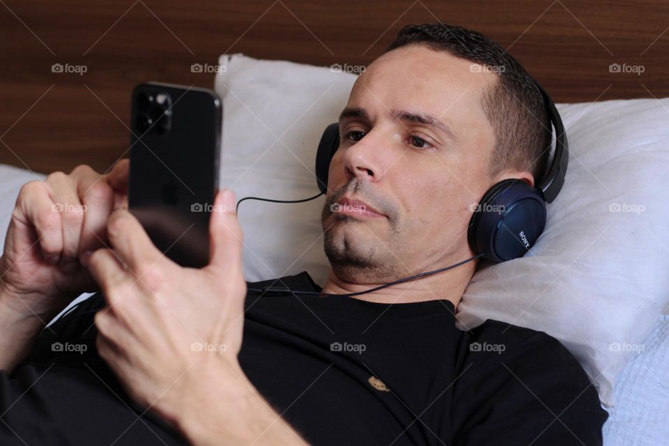 Man relaxing in bed listening to music