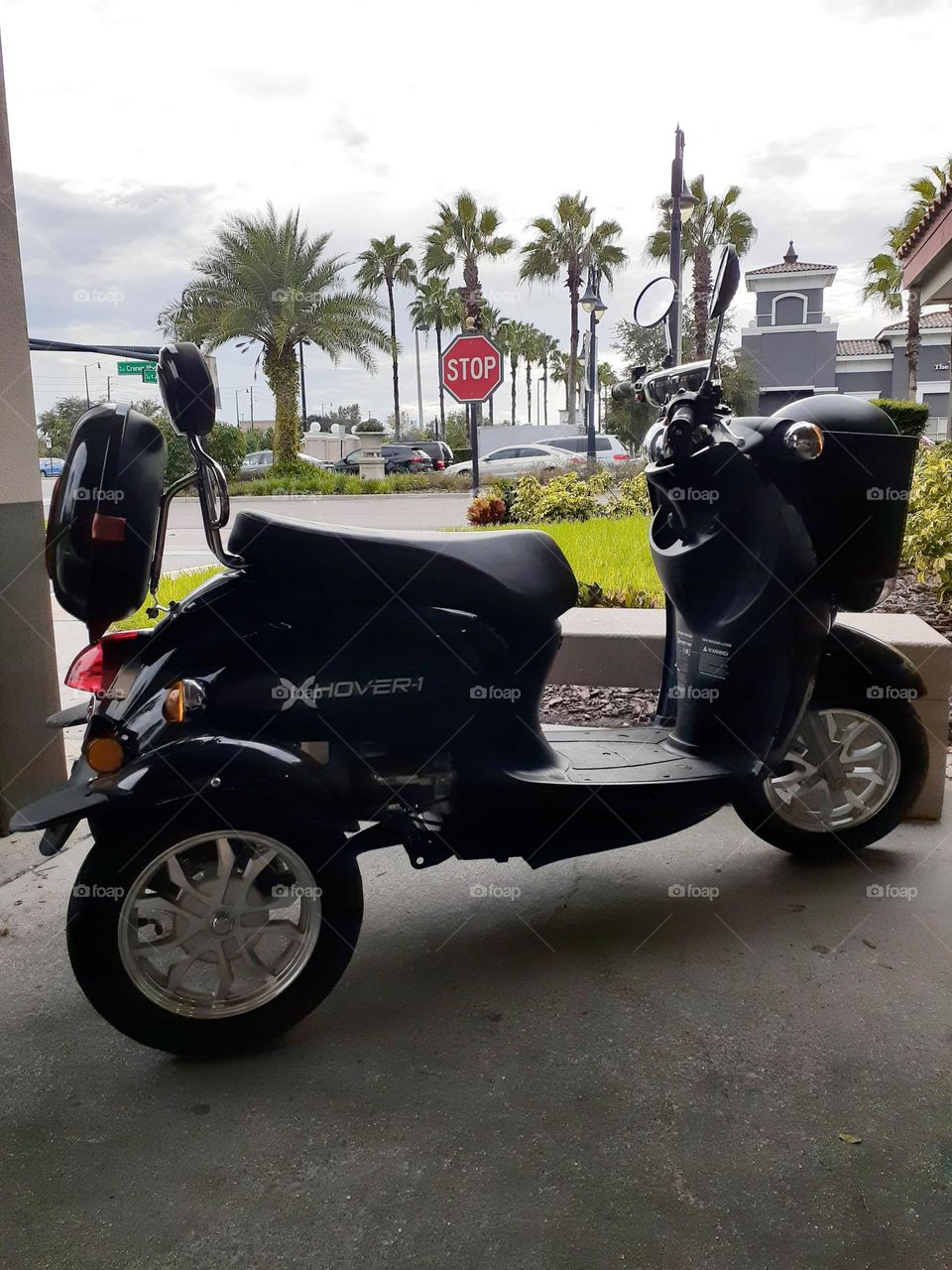 A dark navy scooter parked in the entryway of a Dennys Restaurant while the owner us inside eating.