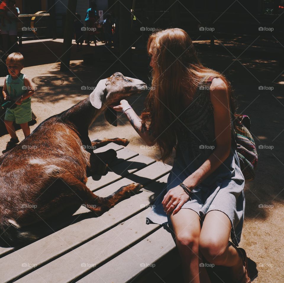 Woman sitting near goat