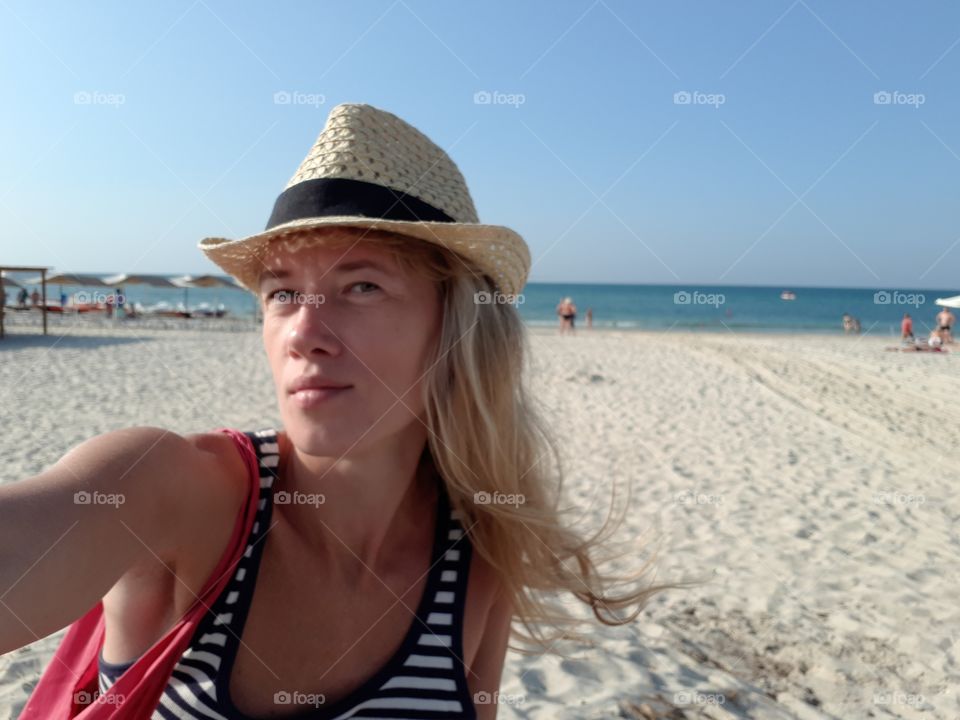 Selfie at the beach of blonde with straw hat