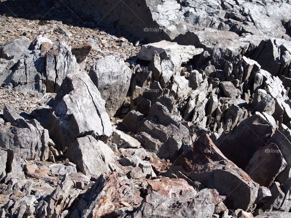 Jagged rocks and boulders along the shoreline of Ochoco Lake in Central Oregon on a sunny spring day.