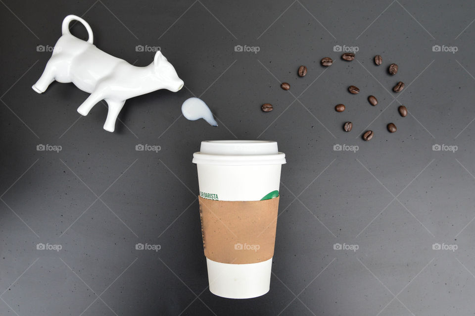 Flat lay of a to go cup of coffee with coffee beans and a splash of cream