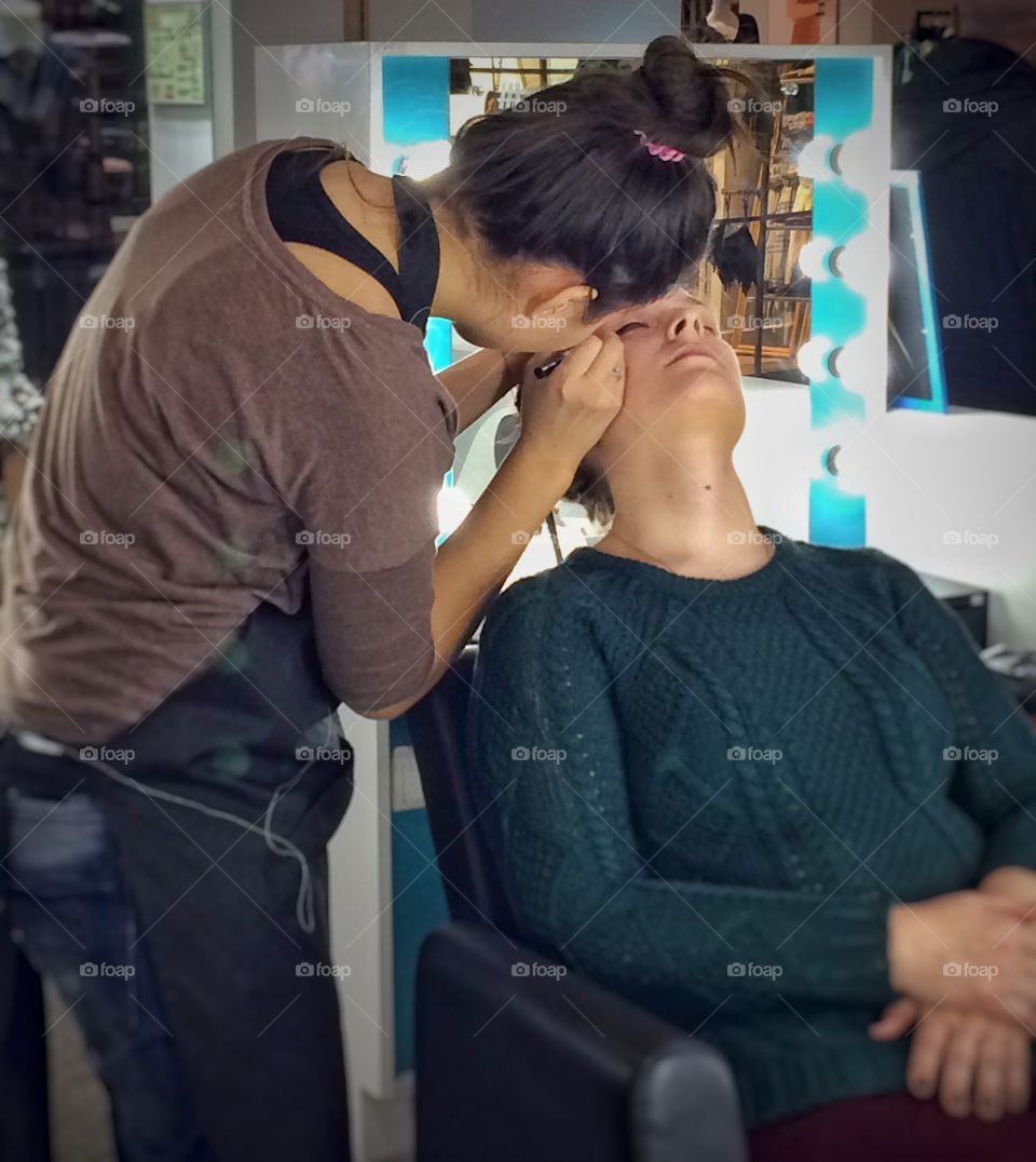 Making beauty. 
I was walking through a shopping mall when I saw this scene. Both of those ladies were busy enough, so I pulled out my phone and made this shot.  