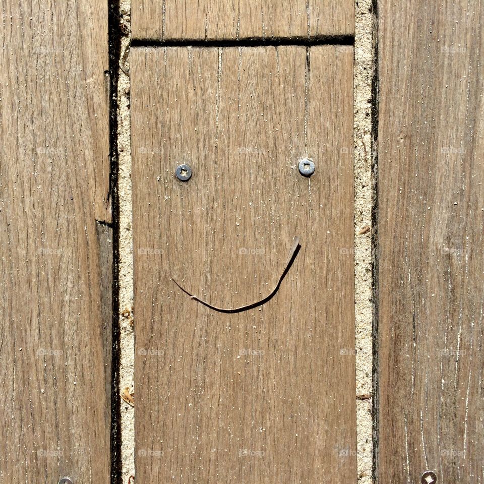 Unsuspecting metallic eyes on Miami Beach boardwalk. Flat lay shot on wood planks. Smiling expression.