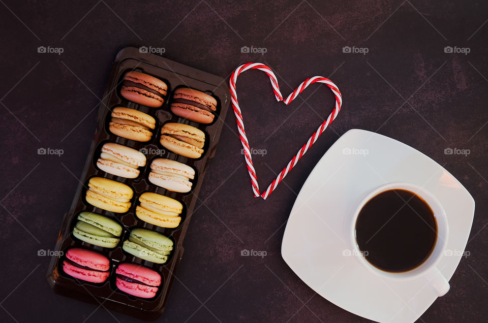 Colorful macaroons and cup of coffee at the black background close up. Flat lay. Top view. Valentine's day. Coffee time.