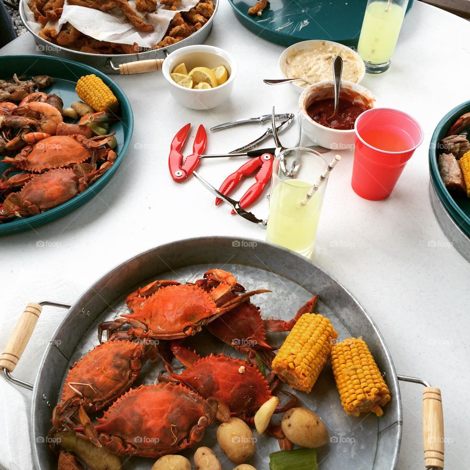 A colorful summer crab boil in south Louisiana. Crabs on steel trays with corn and potatoes, glasses of lemonade with paper straws. A July 4th celebration. 