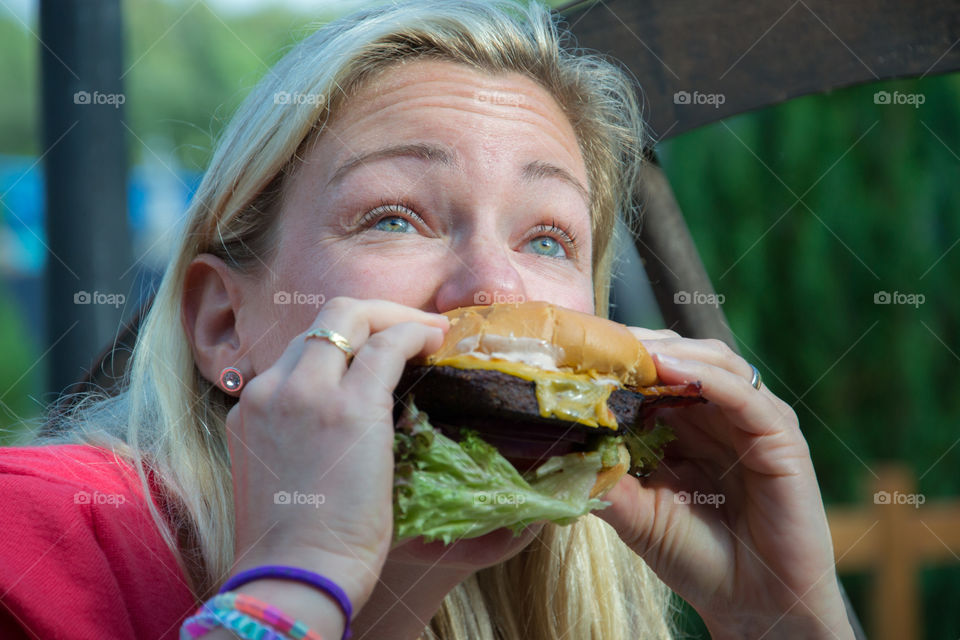 Woman eating big hamburger at restaurant in Halmstad Sweden.