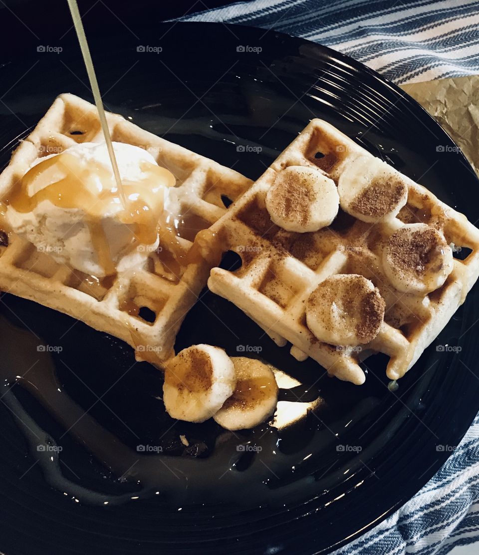 A delicious waffle with ice cream, banana and cinnamon breakfast with golden caramel syrup on top. USA, America 