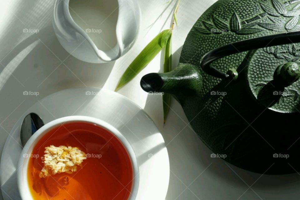 Tea cup and teapot against white background