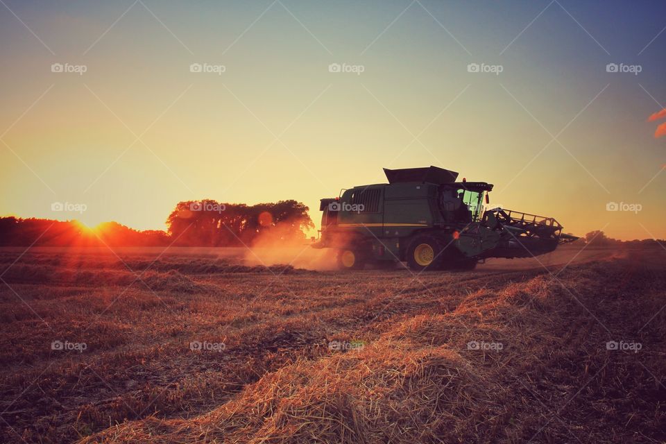 Sunset Harvester. A combine harvester working late into the evening as the sun sets behind it.