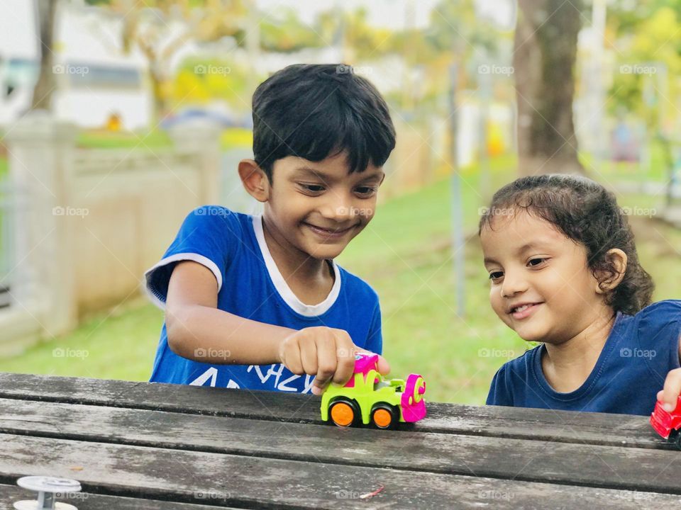 Kids having fun at outdoor by playing together in summertime, they just have a lot of time to play.the boy and girl playing with toy cars out side the house.