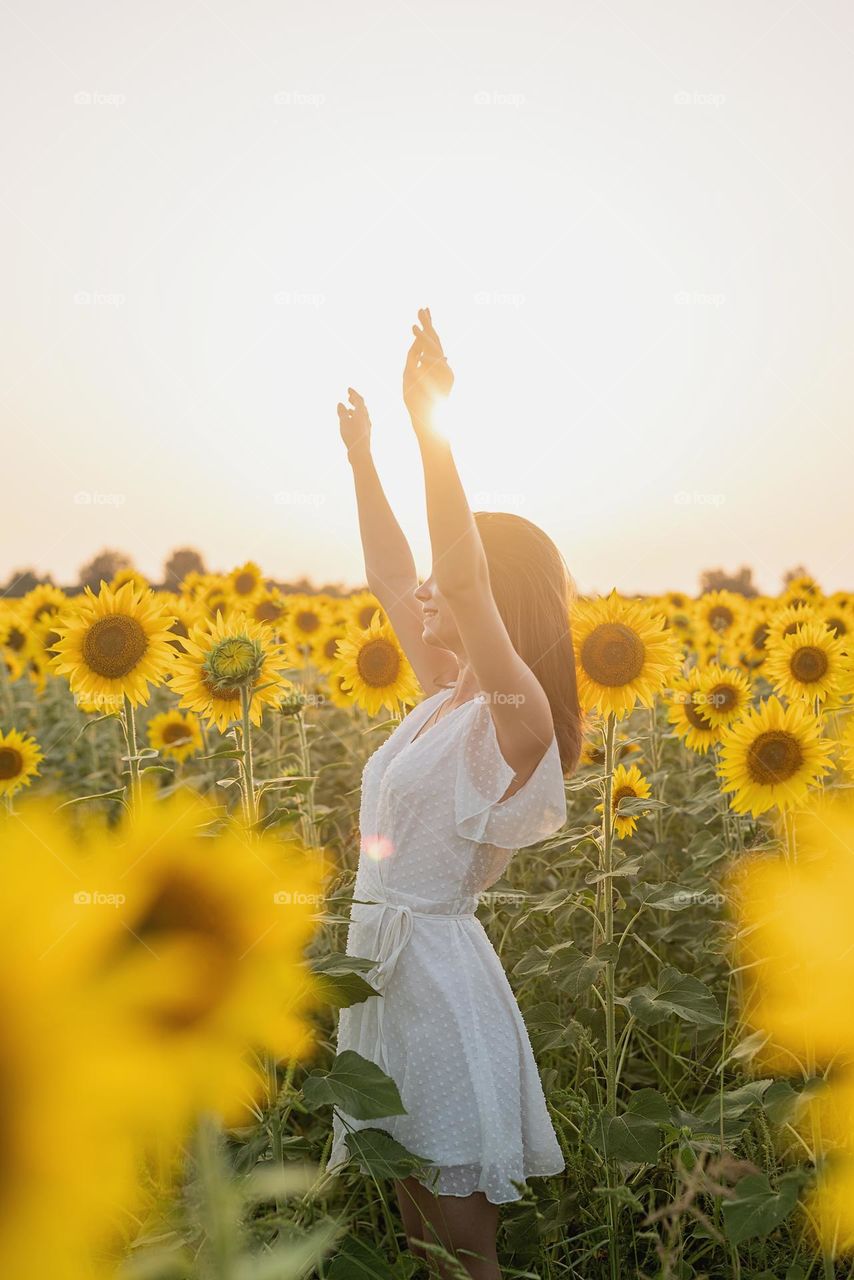 woman in white dress dancing in sunflower field