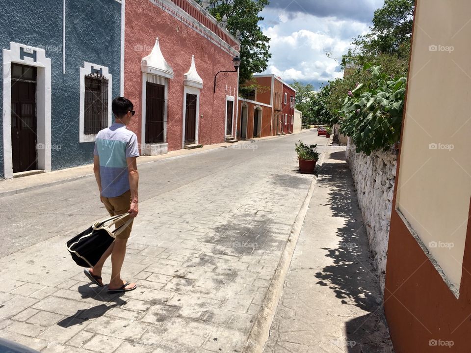 A man strolls down a colorful street in Valladolid, a charming and pristinely maintained Colonial town in Mexico.