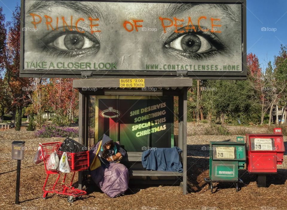 Modern Nativity Scene. Homeless Woman With Baby Under A Bus Stop
