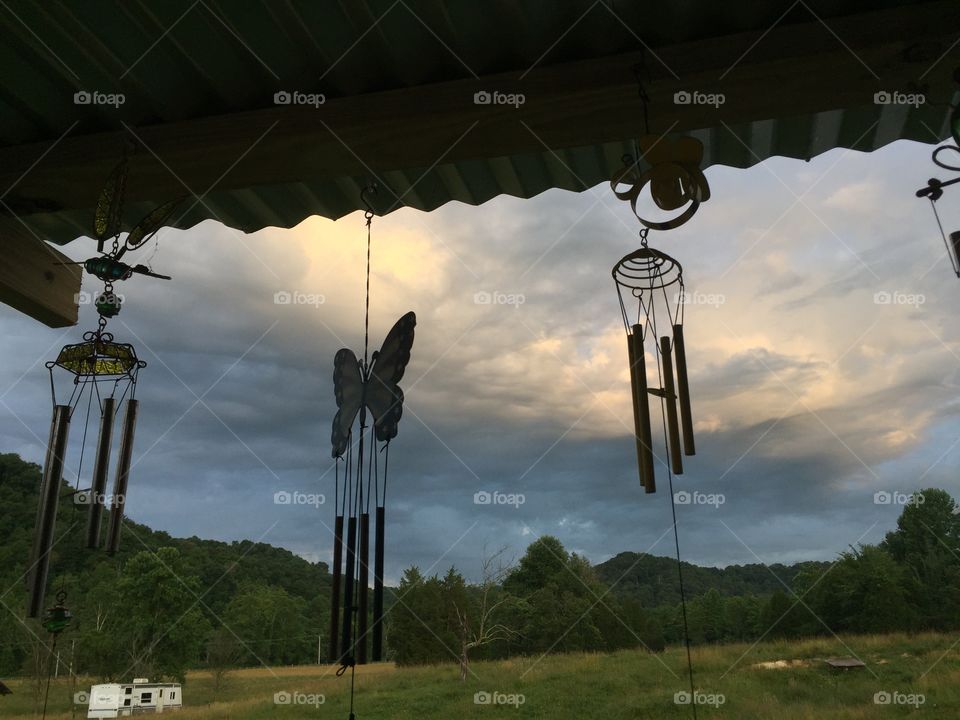 Wind-chimes silhouetted against storm clouds at sunset