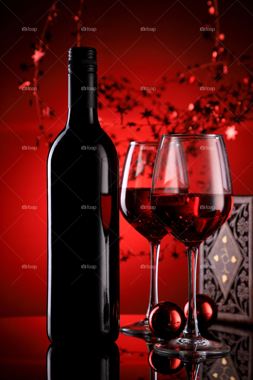 Red Wine glass and bottle with Christmas ornaments in festive holiday feel