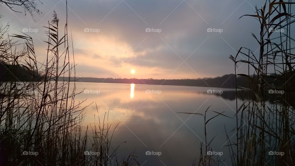 Sunset with reflecting sun and sky in the lake.
