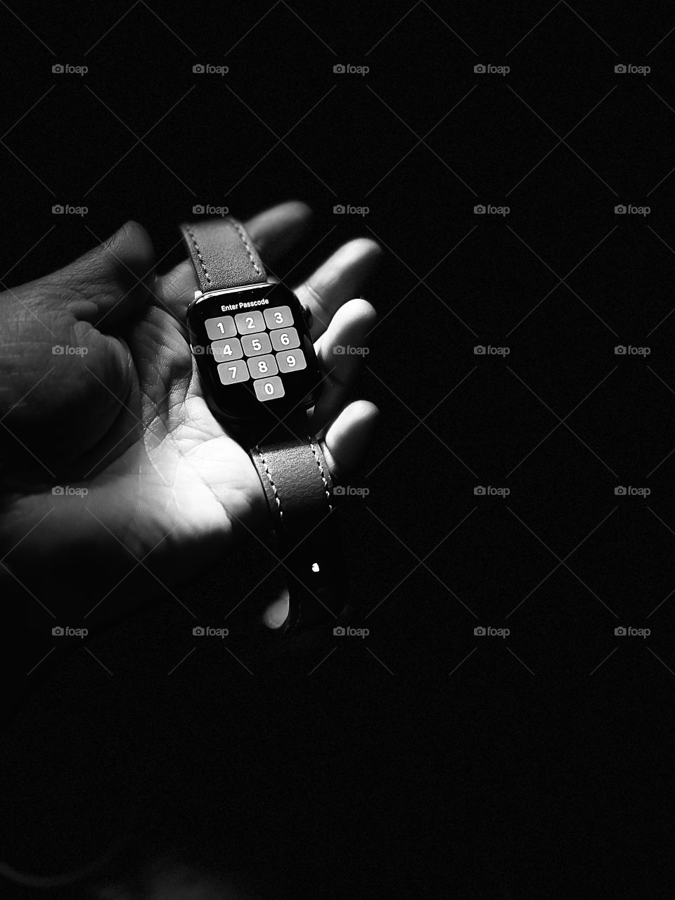 The close up shot of the hand holding the smart watch in the dark with mono light