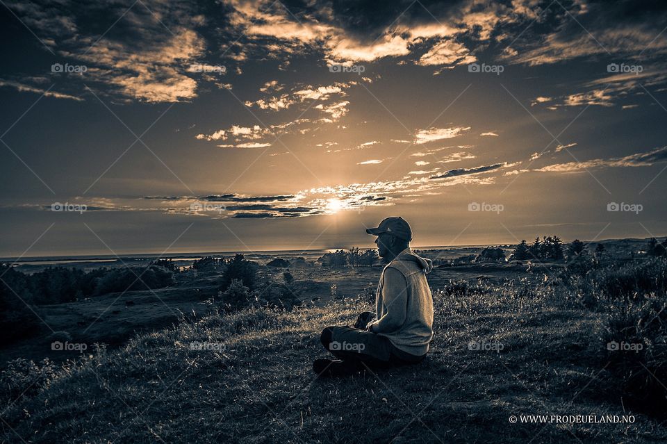 Man sitting on grass during sunset