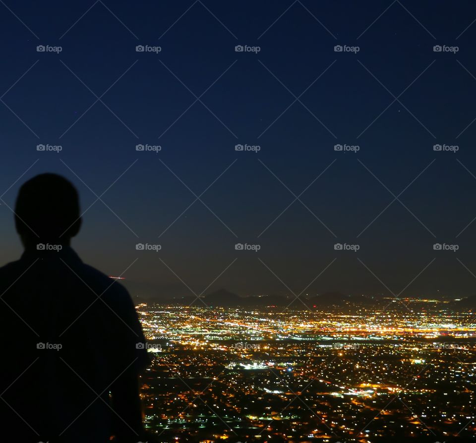 Man standing on mountain top looking at night view 