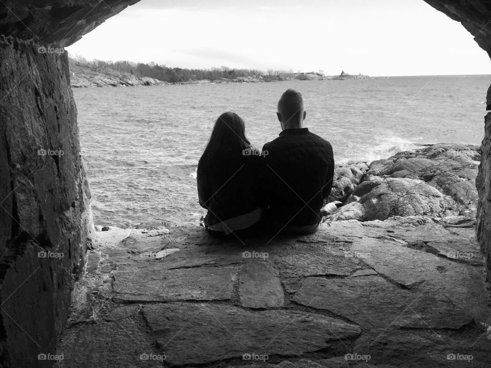 Young couple by the sea. They are enjoying the view and their life together. Black and white picture, from Finland. 