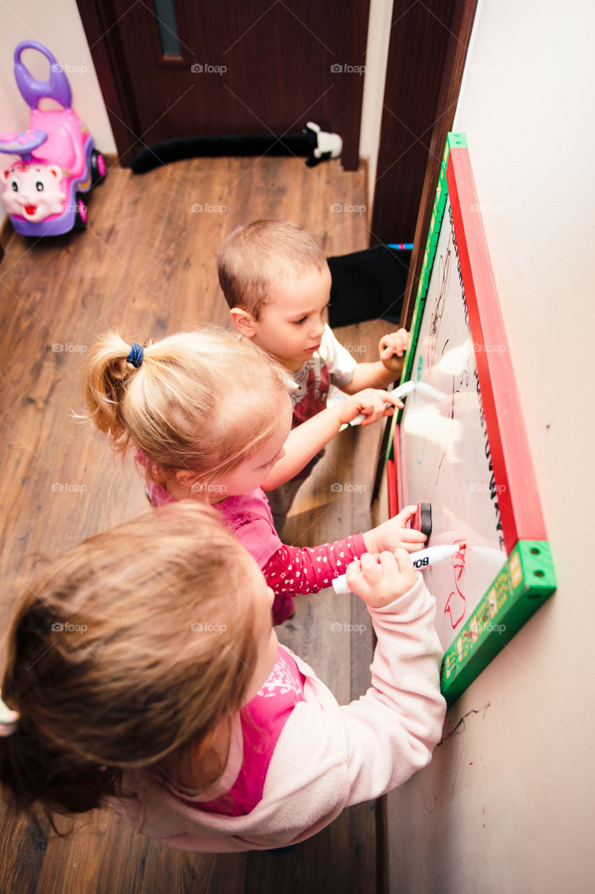 Children drawing a pictures learning a letters playing together using whiteboard and markers