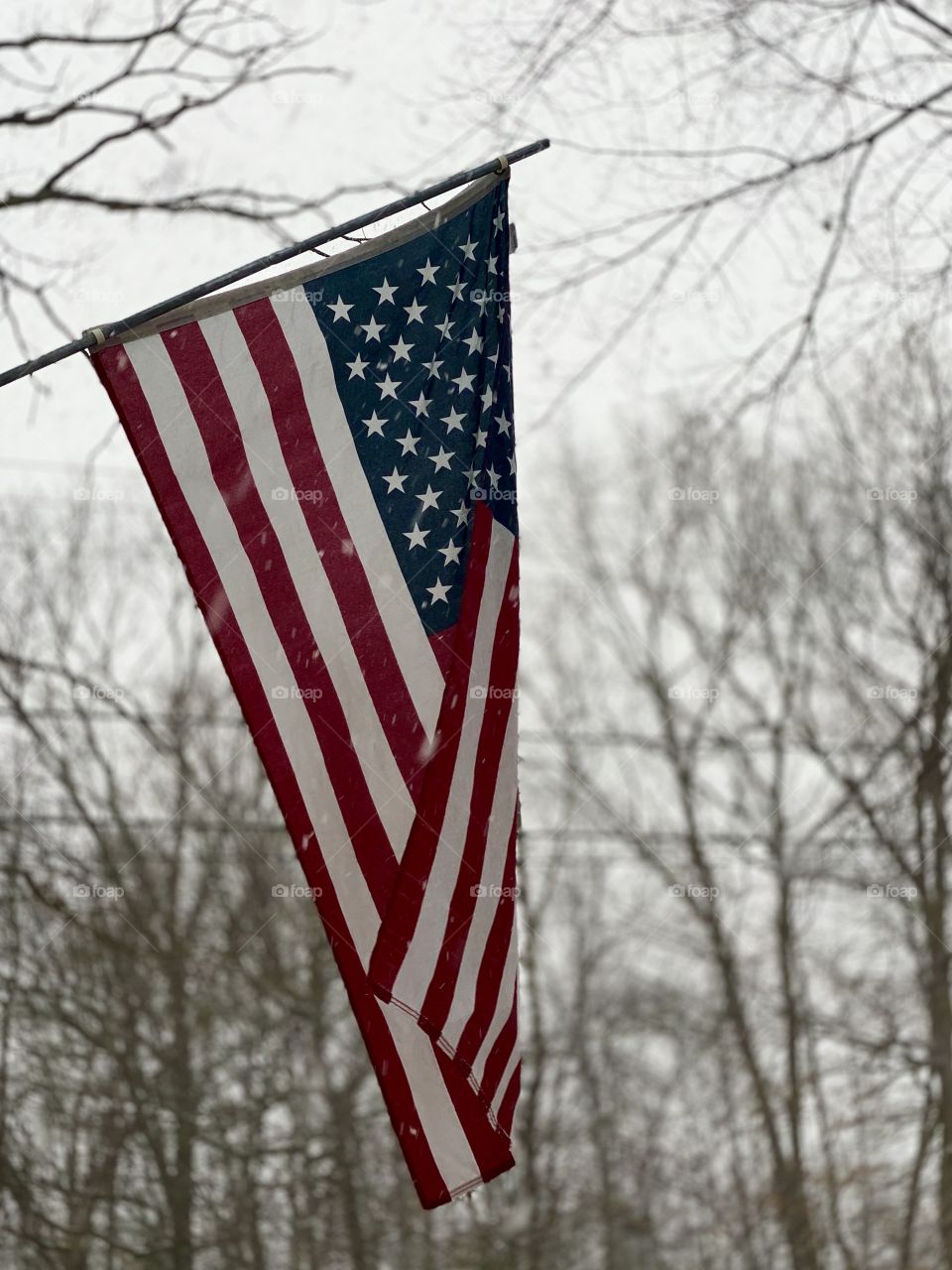 The weather outside is frightful but our Flag makes it look delightful; American Flag settled in a snow storm