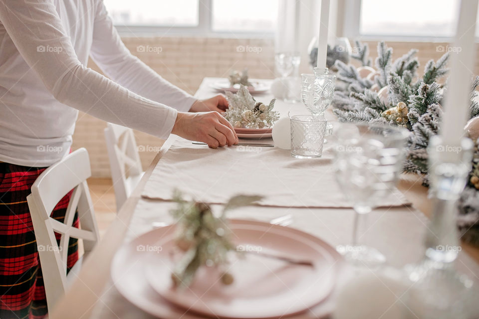 man sets a beautiful decorated winter table for a festive dinner.  Merry Christmas and Happy New Year.