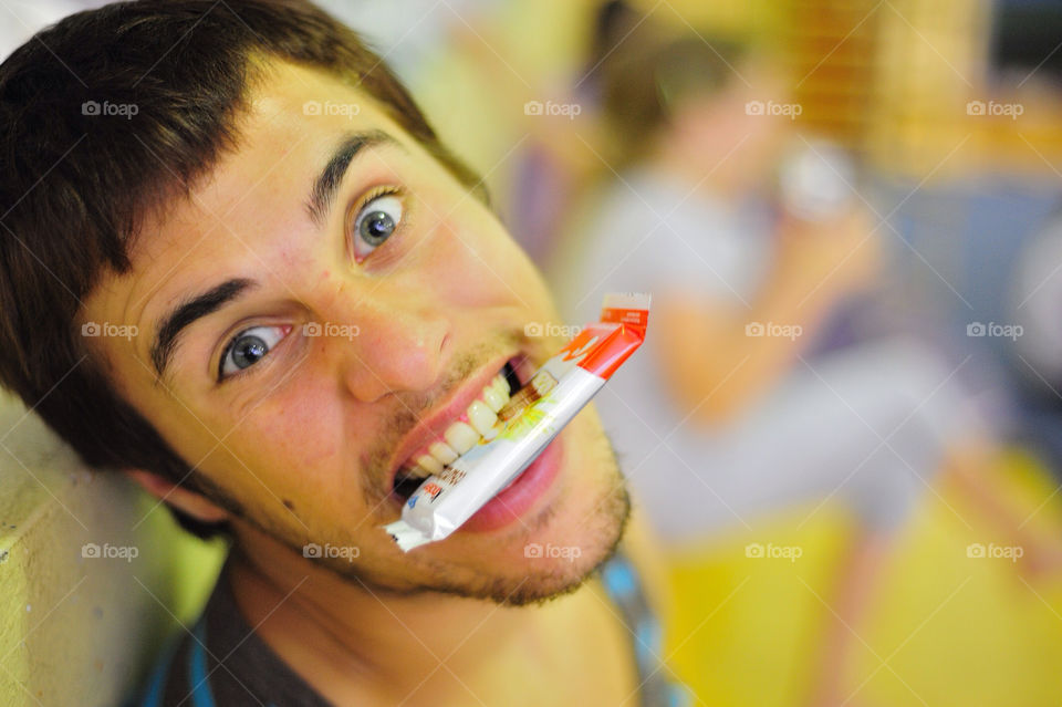 A boy with some chokolate bar in his mouth with wrapping