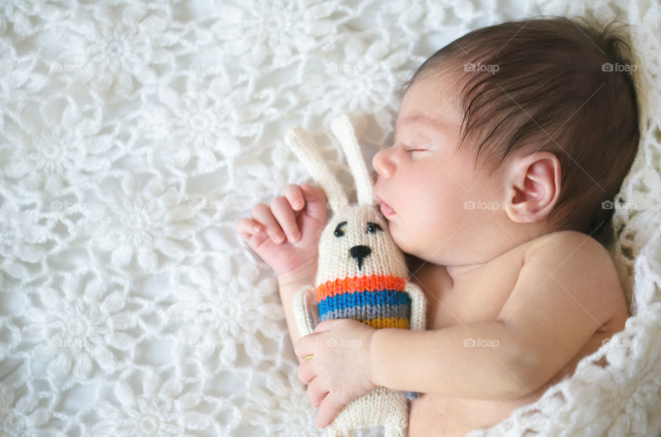 Newborn baby sleeping on bed with soft toy