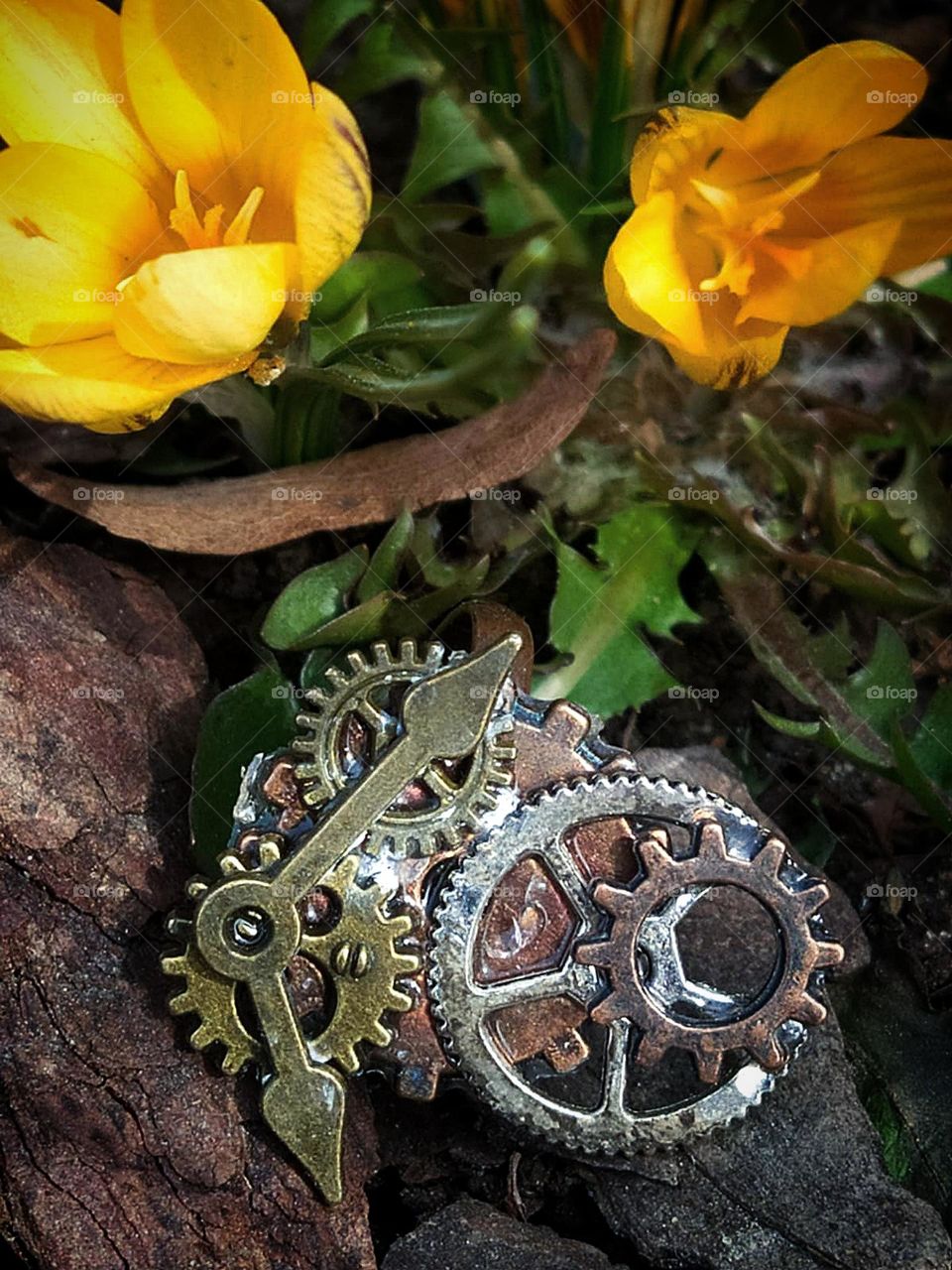 Metal clockwork.  Yellow flowers in the background. Clock gears and hands. Transience of time