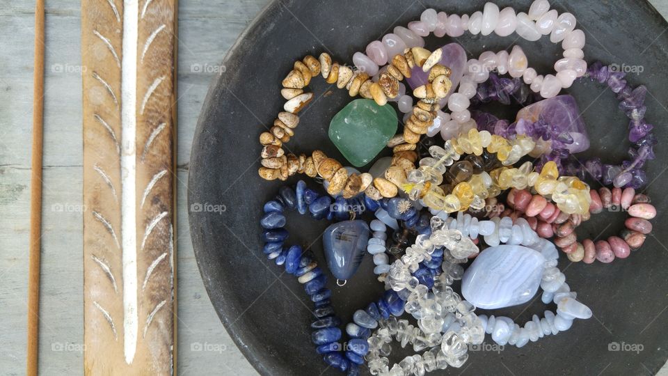 Gem stones in a black bowl on a grey wooden background