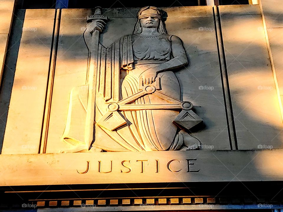 Lady justice stone sculpting on courthouse wall taken at sun down.