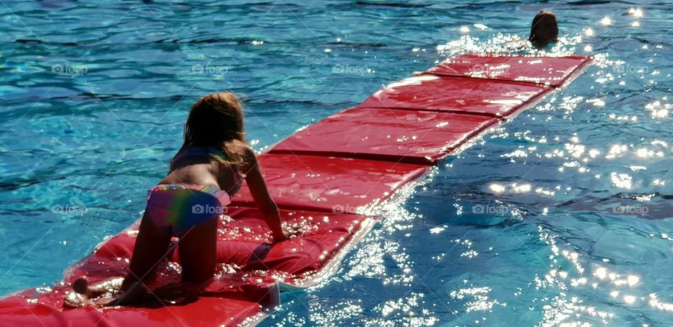 Girl crawling on floater in water