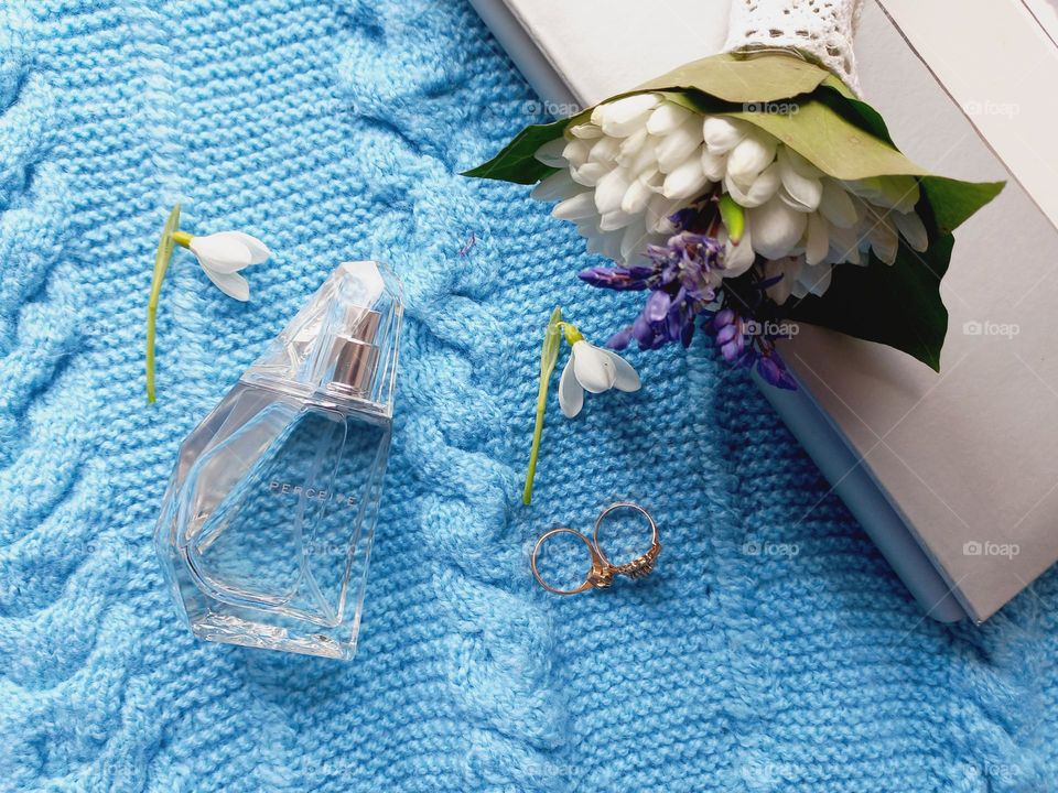 perfume and snowdrops on a blue sweater.