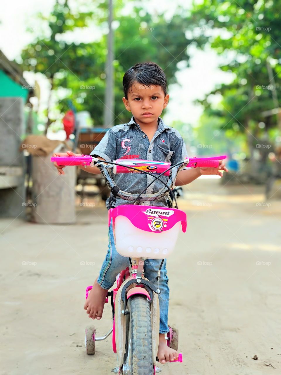 A small boy sitting on small cycle with facial expressions..