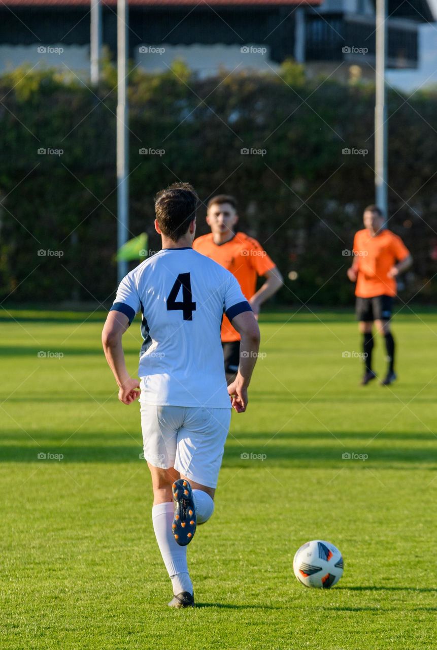 Rear view of professional soccer player in white jersey during match