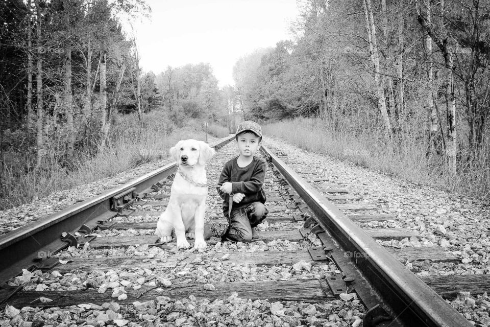 Cute boy with dog on empty rail track
